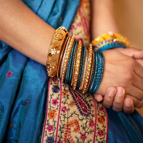 Close up of hands with bracelets resting on a blue sari.