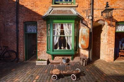 Exterior of a terrace building with green bay window, metal bath, buckets and toys outside.