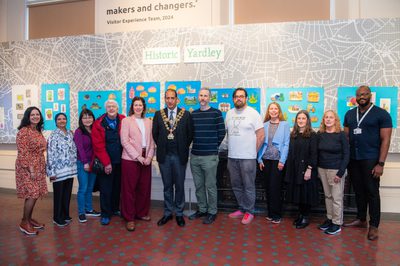 A group of artists and participants and the mayor in front of the Historic Yardley display.