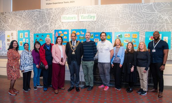 A group of artists and participants and the mayor in front of the Historic Yardley display.