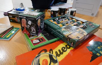 A game of Cluedo games and other Cluedo memorabilia on a table.