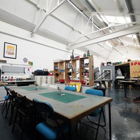 A print works studio space with table chairs in the centre.