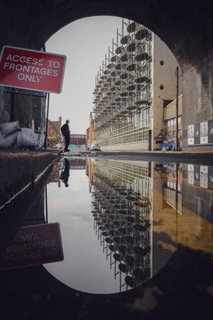 A puddle gives a perfect reflection of the street above it.