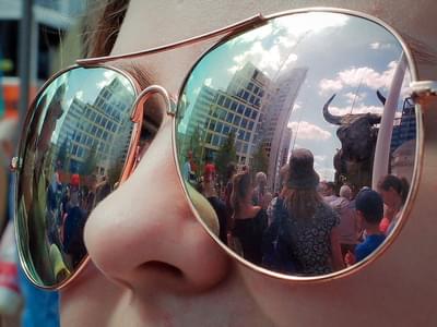 Reflection in a pair of sunglasses shows a crowd looking at the Commonwealth Games bull.