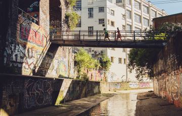Bridge over a canal. Two people are walking across the bridge.
