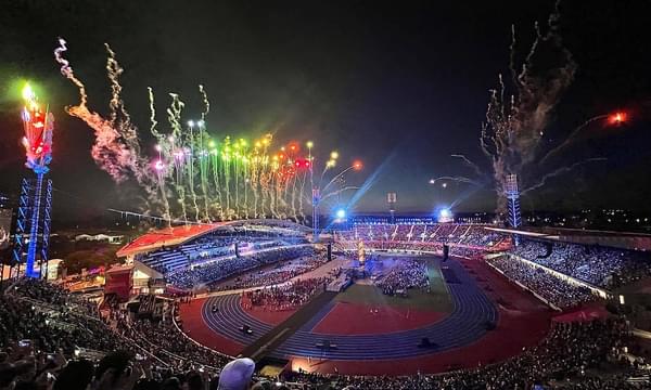 Multicoloured fireworks light the night sky in the stadium packed with people.