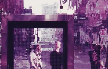 A club entrance. The wall and door covered in lots of small squares of mirrors (like a disco ball). The effect creates a pixelated reflection of the three people in front of the door. The colours are all purple and pinks
