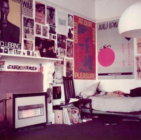 A room with music posters on the walls, a bed and a gas fire