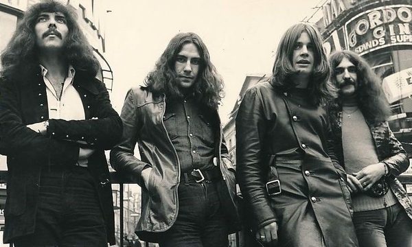 A black and white photo of the members of Black Sabbath standing outside in 1970.