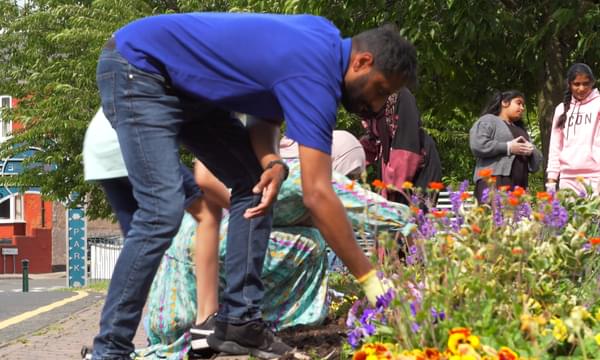 A small group of people are tending flowers in a park.