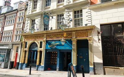 An exterior of an old pub building with a yellow and blue entrance.