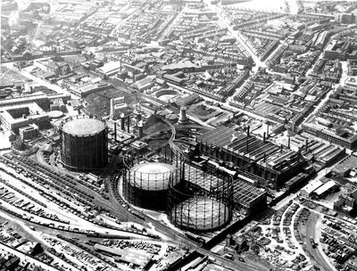 Aerial view of three Gasholders surrounded by a factory, houses and roads, c1950.
