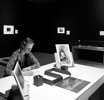 Fae sitting at a desk at work in an exhibition.