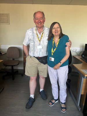 Two volunteers standing together smiling.
