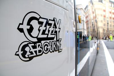 A close up of Ozzy Osbourne's name written on the side of a tram. The S letters are written as Z letters. The outline of the letters are in black and the inside of the letters are white. It is on a white background.