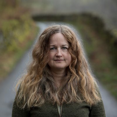 A lady standing outside in a country lane.