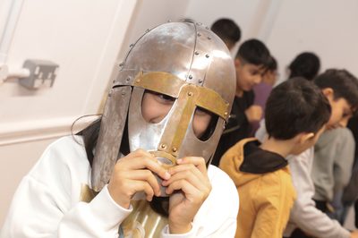 A child wearing and holding on to a replica Staffordshire Hoard helmet.