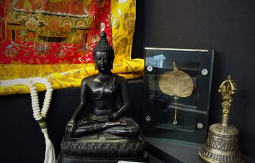 Buddhist items including Prayer beads, Guanyin statue, Buddha Rupa, embroidery, bell, fragment of frieze, bodhi leaf.