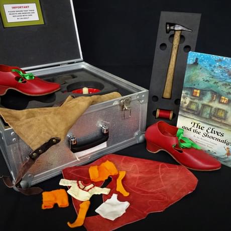 The Elves and the Shoemaker story book with shoes, tools and loans box.