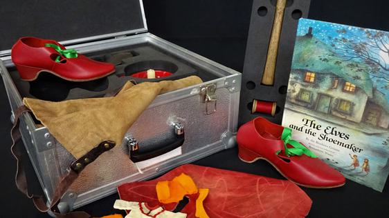 The Elves and the Shoemaker story book with shoes, tools and loans box.