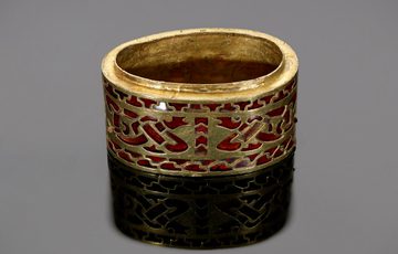 A gold and garnet hilt collar. It's has a very intricate design, featuring serpents. It's on a grey background.