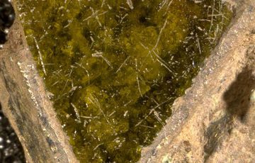 a close up photograph of a glass triangle, set into an object. The glass is green.