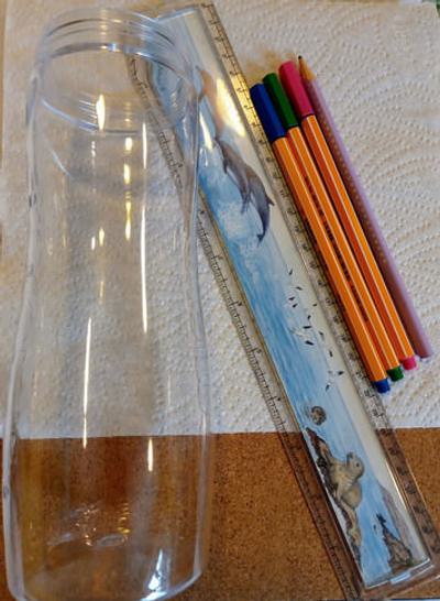 A photo of paper, pencil, pens, a plastic container, and a ruler
