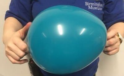 A photo of someone holding a green balloon with both hands