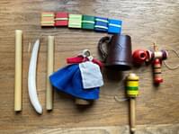 A series of items on a wooden table. Includes a leather cup, some wooden toys and some candles