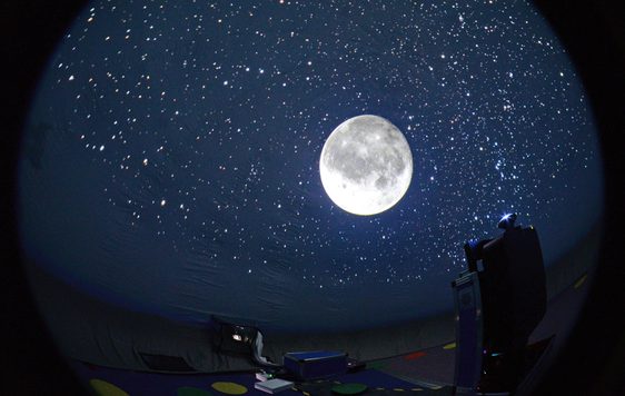 Inside a mobile planetarium with stars and moon in the night sky.