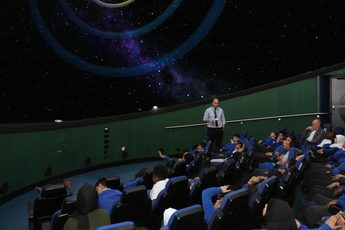 A group of school children sitting watching a planetarium show.