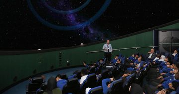 A group of school children sitting watching a planetarium show.