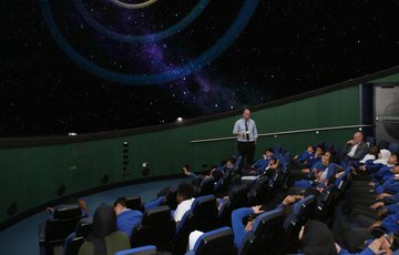 A group of school children sitting watching a planetarium show.