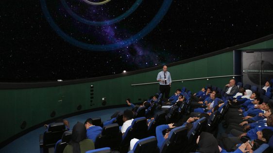 A group of school children sitting watching a planetarium show.