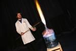 A staff member doing a science experiment with fire and flames shooting out of a bottle