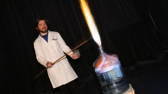 A staff member doing a science experiment with fire and flames shooting out of a bottle