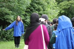 A learning officer standing outside, talking to a group of teachers and children who are walking away out of shot.