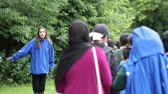 A learning officer standing outside, talking to a group of teachers and children who are walking away out of shot.