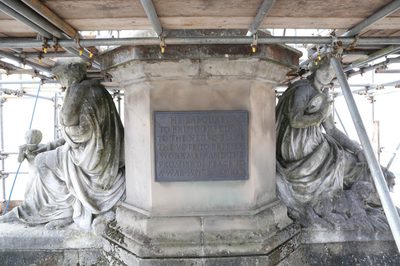 Plaque on a plinth and on either side two figures of Peace and Charity in need of conservation and cleaning.