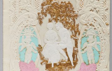 Intricate lacework card with a romantic couple, cherubs, floral accents, and "A Lovers Gift" banner at top.