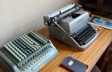 A desk with typewriter and machine on it.