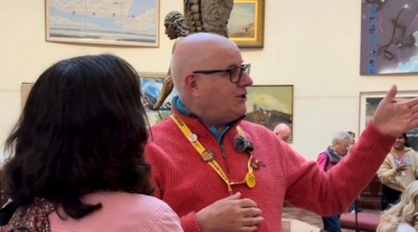 A volunteer talking to a visitor in a gallery setting.