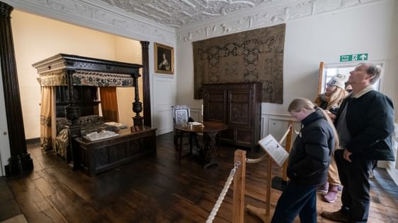 Visitors in the a bedroom with four poster bed.