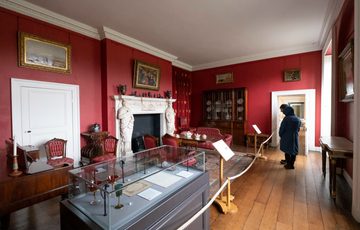 Visitors in the room painted red with furniture and and fireplace.