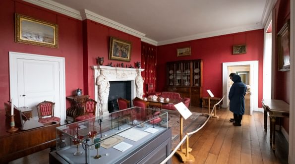 Visitors in the room painted red with furniture and and fireplace.