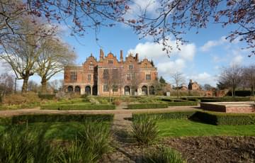 Exterior view of the rear of a Jacobean Hall and garden.