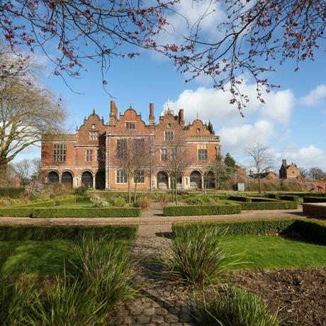 Exterior view of the rear of a Jacobean Hall and garden.