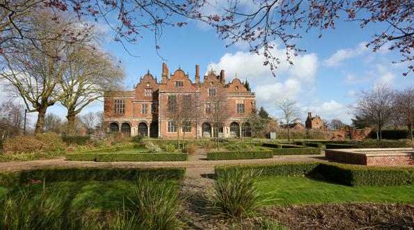 Exterior view of the rear of a Jacobean Hall and garden.