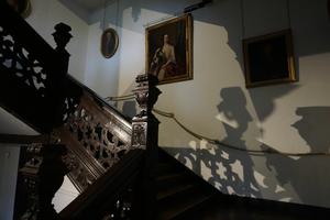 The stairs at Aston Hall at night. Shadows of the wooden staircase can be seen on the walls.