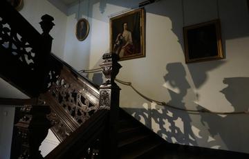 The stairs at Aston Hall at night. Shadows of the wooden staircase can be seen on the walls.